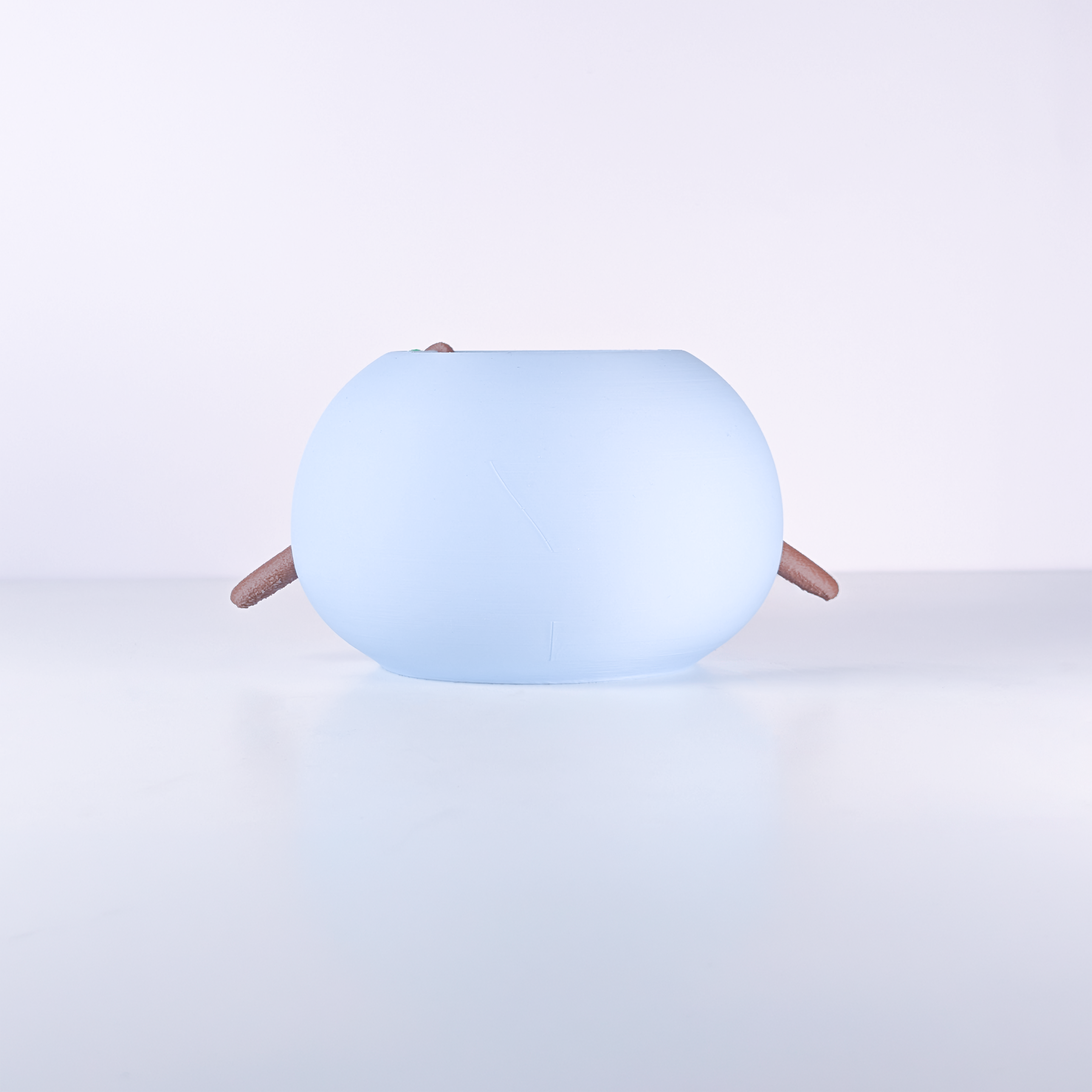 A light blue, rounded, egg-shaped device with small brown legs, photographed on a clean white studio background.